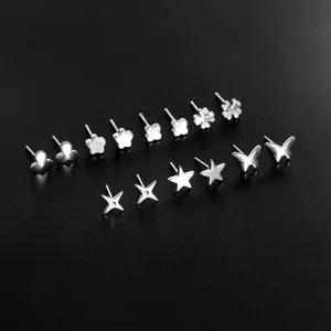 Primer plano detallado que muestra varios pendientes de tuerca plateados con trébol y estrella.