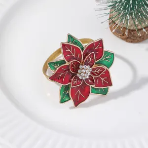 Close-up of Christmas poinsettia napkin ring with red enamel petals, green leaves and rhinestones.
