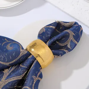 Nahaufnahme des goldenen Trommel-Serviettenrings mit blauem Mustertuch für Tischdekoration.