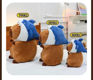 Cute capybara plush toy wearing blue shark hat, soft stuffed doll size detail display.