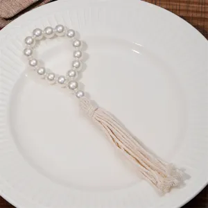 Pearl tassel napkin ring detail shot, showing elastic bead string and woven cotton cord.