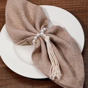 Close-up of elegant pearl and tassel napkin ring detail, perfect for modern table decor.