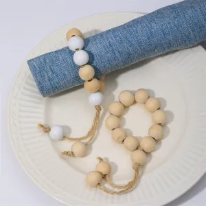 Handcrafted wooden bead napkin ring detail showing natural wood and white beads with jute tassel.