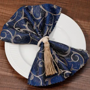 Elegant blue and gold patterned napkin cloth with wooden bead and twine tassel ring for dining.