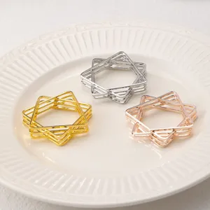 Close-up detail of geometric star metal napkin rings in gold, silver and rose gold.