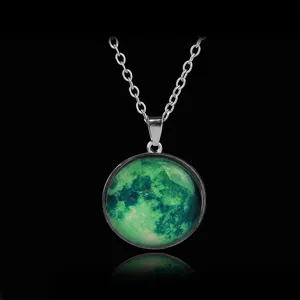 Close-up view of a glowing green moon glass dome pendant necklace with silver chain detail.