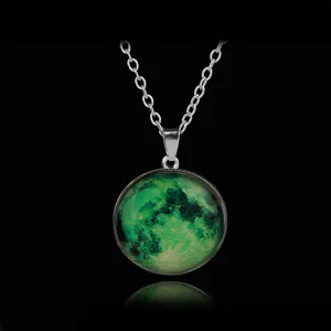 Close-up detail of a glowing moon pendant necklace with a green luminous pattern on black.