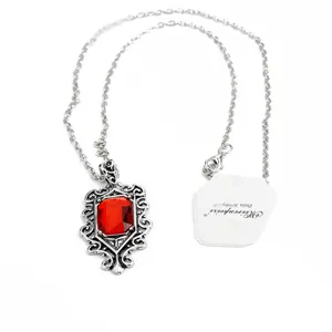 Gros plan détaillé du collier argenté de style vintage avec un pendentif en pierre rouge.