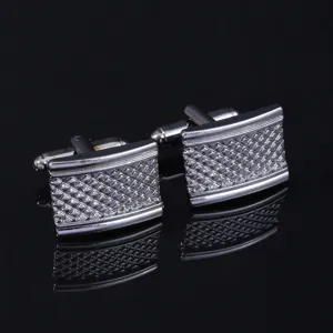 Close-up detail shot of metallic square cufflinks featuring fine grid carved patterns for men.