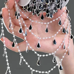 Gros plan sur la chaîne de perles DIY avec de élégants pendentifs goutte d'eau noirs.