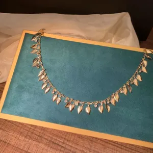 Detail shot of golden leaf zircon chain accessory, delicate swinging design for versatile styling.