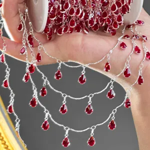Close-up detail of ruby red teardrop zirconia charms on shiny silver DIY jewelry chain.