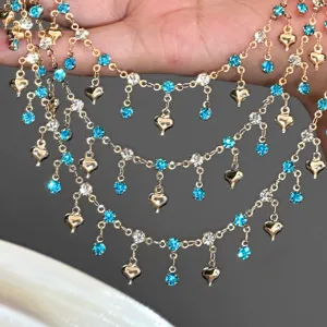 Detailed close-up of DIY multi-layer gold chain with blue rhinestones and heart charms.
