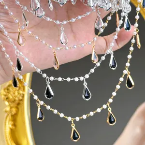 Gros plan détaillé de chaînes de perles DIY superposées avec pendentifs en forme de goutte.