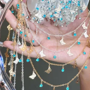 Close-up of DIY metal chains with blue rhinestones and butterfly charms for craft.