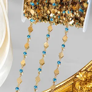 Chaîne dorée DIY avec plaques métalliques en losange et strass bleus pour création de bijoux.