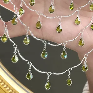 Detailansicht der mehrreihigen silbernen Kette mit funkelnden grünen tropfenförmigen Zirkonanhängern.