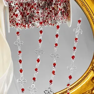 Gros plan sur une garniture de chaîne en métal argenté DIY avec des strass rouges et des motifs.