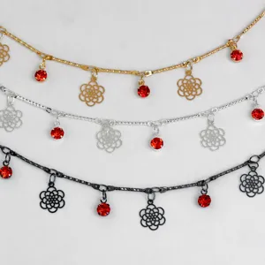 Close-up detail of DIY decorative metal chain with red rhinestones and hollow floral pendants.