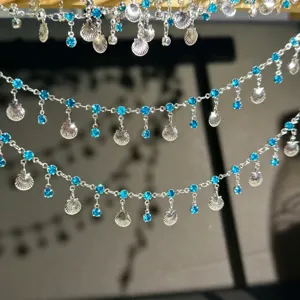 Close-up detail of silver DIY hair accessory chain with blue rhinestones and shell pendants.