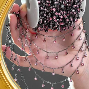 Close-up detail of dark metal chain with pink rhinestones for DIY handmade jewelry crafts.