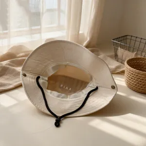Vista detallada del sombrero de pescador beige para niños con barbilla ajustable y forro.