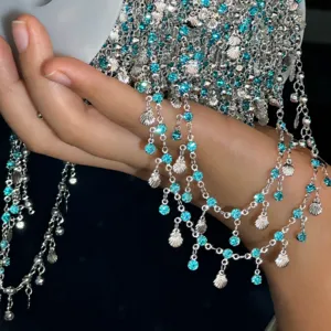 Vue rapprochée détaillée de la chaîne en cuivre DIY avec des strass bleus et des breloques coquillage.