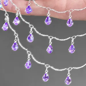 Close-up detail of multi-strand silver-plated chain with purple teardrop zircon charms.