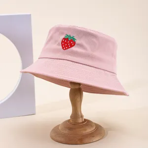Primo piano del cappello da pescatore rosa con ricamo di fragole rosse per la protezione.