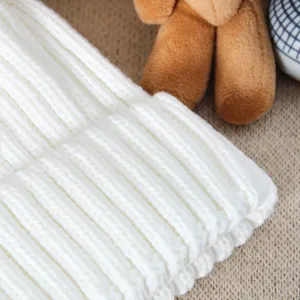 Close-up detail of white ribbed knit winter beanie hat, showing thick soft warm texture.