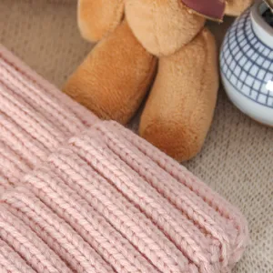 Women pink knitted beanie hat detail close up shot, cozy winter warm wool cap texture view.