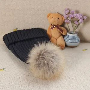 Detailed view of the black knit winter beanie featuring a fluffy fur pom-pom and cozy warm texture.