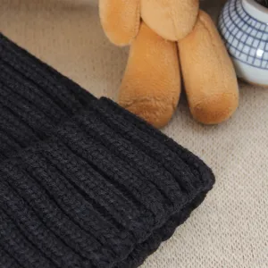 Black ribbed knit winter beanie hat detail view, thick warm woolen cap for women casual daily wear.