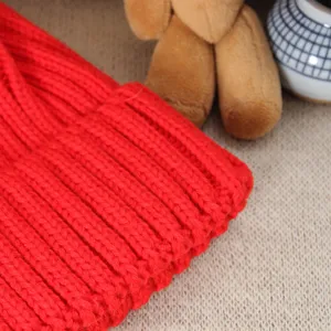 Close up detail of a vibrant red winter knitted beanie showing soft ribbed texture.