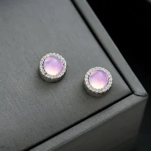 Primer plano detallado de pendientes magnéticos redondos de piedra rosa con strass.