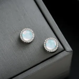 Detalle de pendientes de clip redondos iridiscentes con un halo de pedrería brillante.