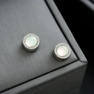 Primer plano detallado de pendientes magnéticos de ópalo con halo de diamantes de imitación.