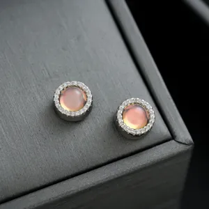 Elegantes pendientes redondos con piedras rosas en el centro y detalles de pavé de cristal.