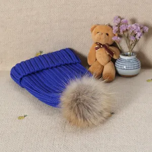 Detailed view of royal blue knit beanie featuring a fluffy faux fur pom-pom winter hat.