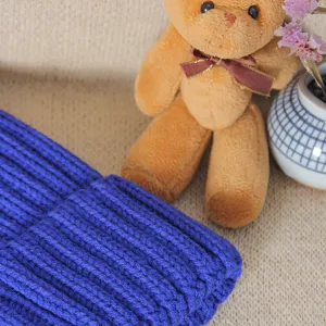 Close-up view of a cozy blue knitted winter beanie hat showing thick rib texture and soft warm fabric.