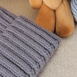 Grey ribbed knit winter hat detail view showing soft woolen fabric texture and cozy design.
