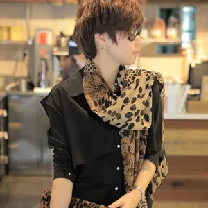 Plano detalle de un elegante pañuelo de gasa con estampado de leopardo en un café.