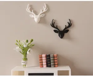 Détail déco murale miniature tête de cerf noire et blanche pour scène de maison de poupée.