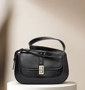 Detail of black vintage leather shoulder bag with metallic twist lock and contrast stitching.