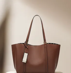 Detailed view of brown leather tote bag showing fine craftsmanship, vertical lines and stylish tag.