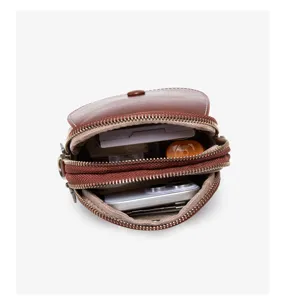 Detail view of brown leather multi-compartment mini cross body phone bag with zipper.