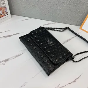 Black punk style skull embossed envelope crossbody bag with metal chain strap for women fashion use.