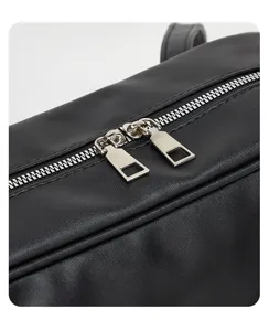 Detailed close-up view of the black leather shoulder bag showing smooth metal zippers and stitching.