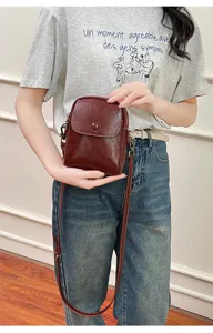 Close-up detail of dark red small crossbody phone bag with strap and front snap button.