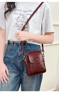 Detailed view of a stylish dark red crossbody small square bag worn by a model daily.